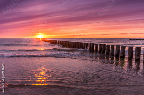 Baltic sea coast on colorful sunset with wooden groyne, Poland © tomeyk