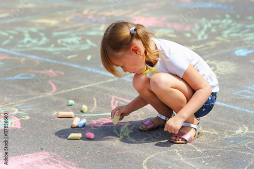 little girl draws a chalk