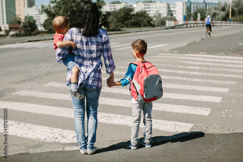 Mother and her children standing at a crosswalk on their way to school
