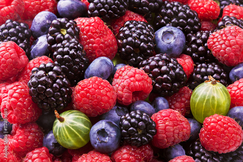 Blueberries, raspberries, blackberries and gooseberries background shot top down. Top view.