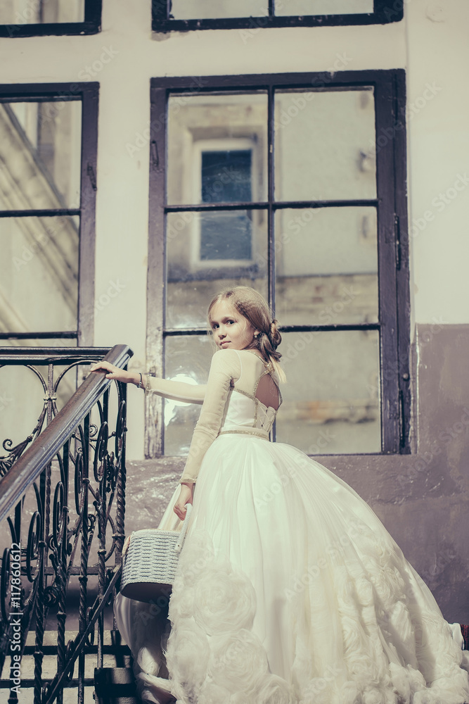 Fototapeta premium small girl in white dress near big window