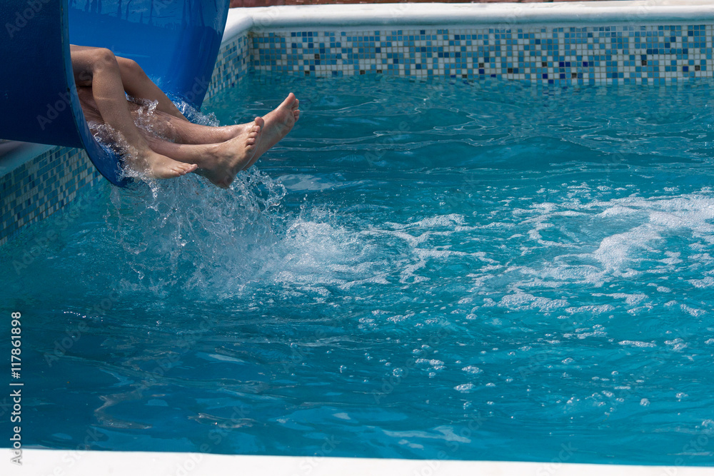Legs of tourists descending on a slide in the pool. Recreation