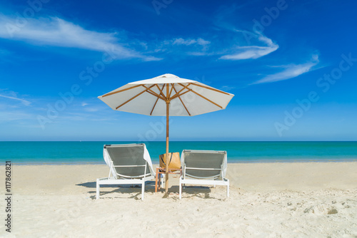 Beach chairs on the sand beach with cloudy blue sky