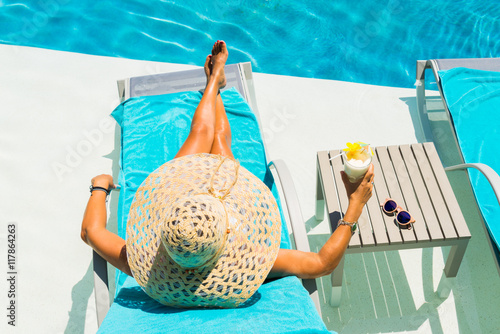 Cuadro en lienzo Woman at the poolside with pina colada cocktail