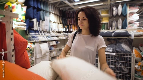 Pretty, young woman choosing a pillow in shop photo