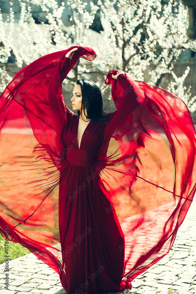Fototapeta premium Girl in red dress near blossom