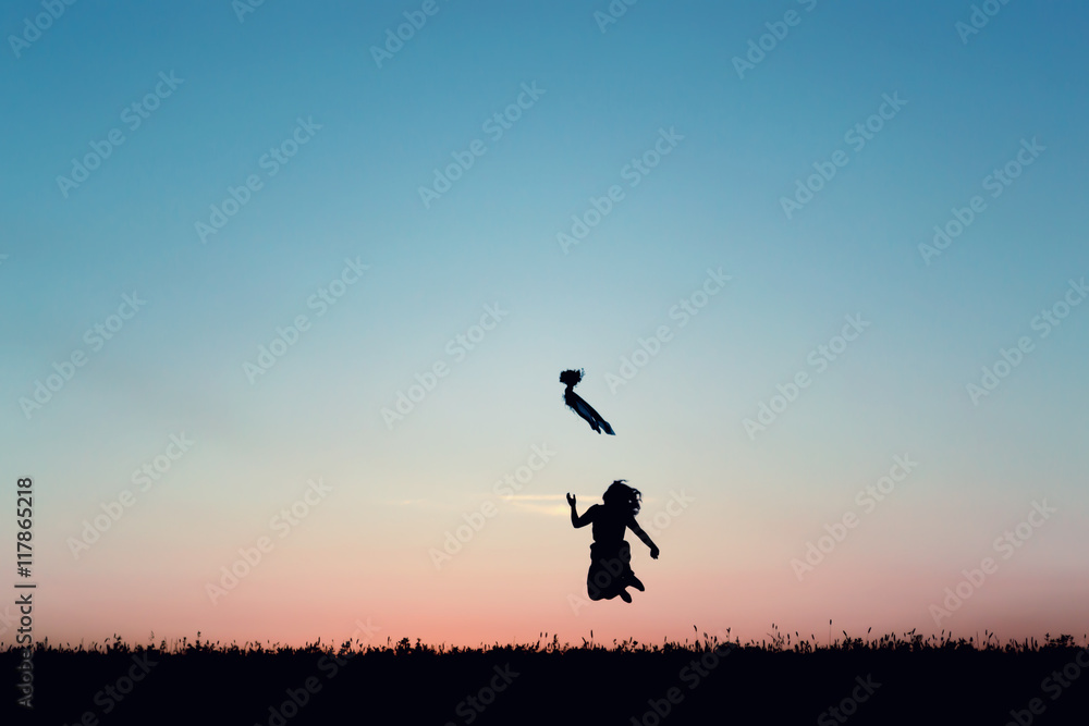 Silhouette of a beautiful girl jumping over sunset