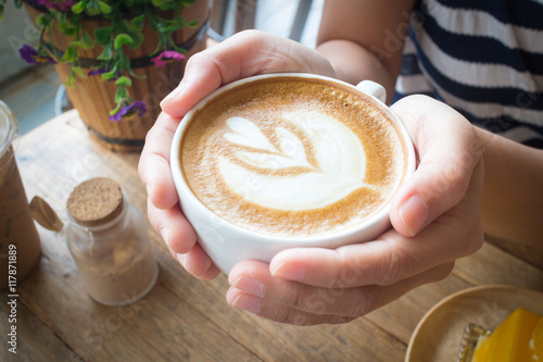 Woman holding hot cup of coffee, with heart shape