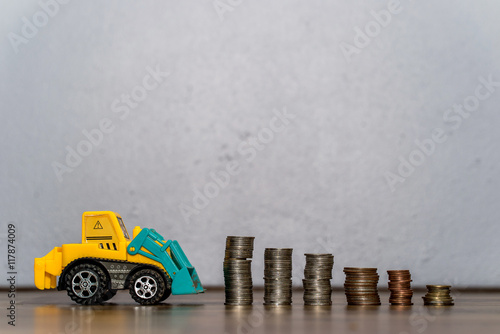 business and money concept - Tractor toy downloading a coins stack
