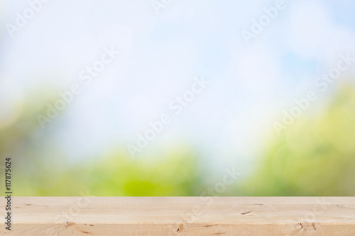 Wooden table with natural green and blue sky background.