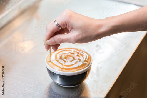 Barista creates a caramell picture in a cup of coffee latte
 photo