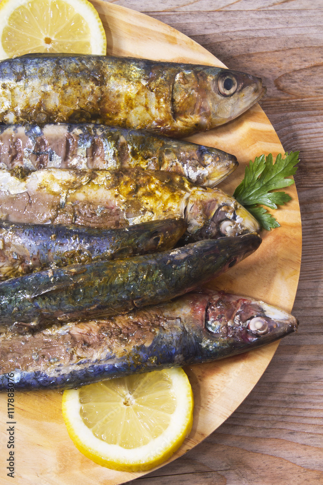 fish dish, grilled sardines with lemon on wooden background fish dish, grilled sardines with lemon on wooden background