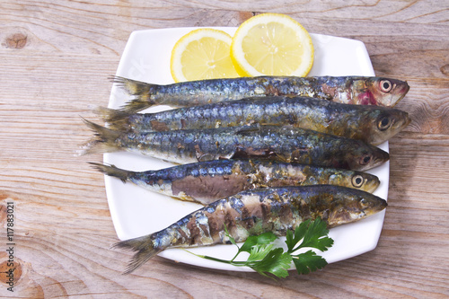 fish dish, grilled sardines with lemon on wooden background