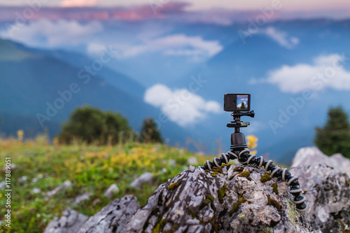 Action camera with selfie pole on the peak of mountain