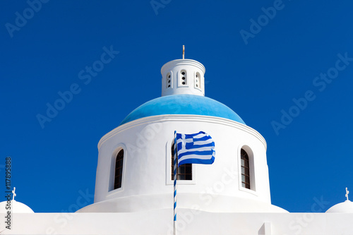 Greek national flag wavin, with a blue church dome in the background