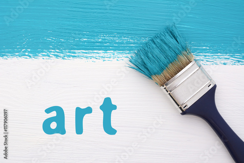 Stripe of turquoise paint, paintbrush and the word ART