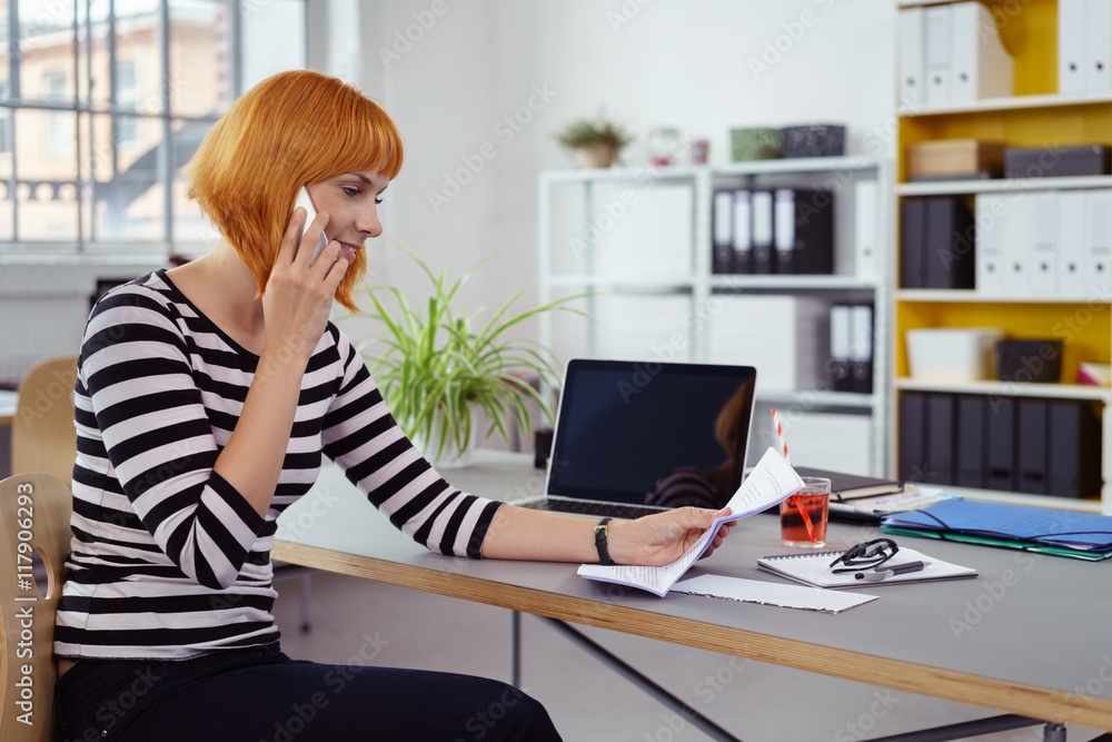frau im büro telefoniert und schaut auf einen brief frau im büro telefoniert und schaut auf einen brief