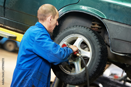 auto mechanic screwing car wheel by wrench © Kadmy
