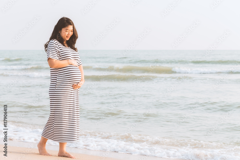 Pregnant woman holding her belly on the beach with copy space. Pregnant woman holding her belly on the beach with copy space.