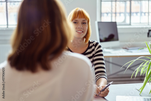 zwei frauen sitzen sich im büro gegenüber in einer besprechung photo