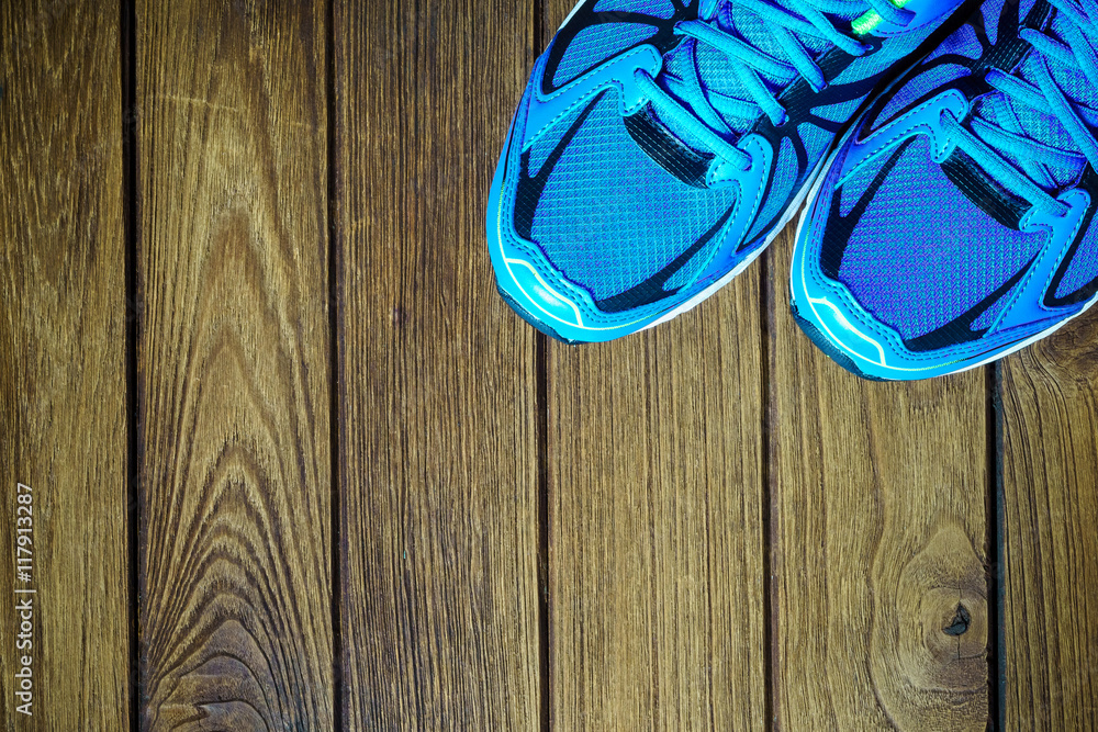 Blue running shoes on wooden background Top View