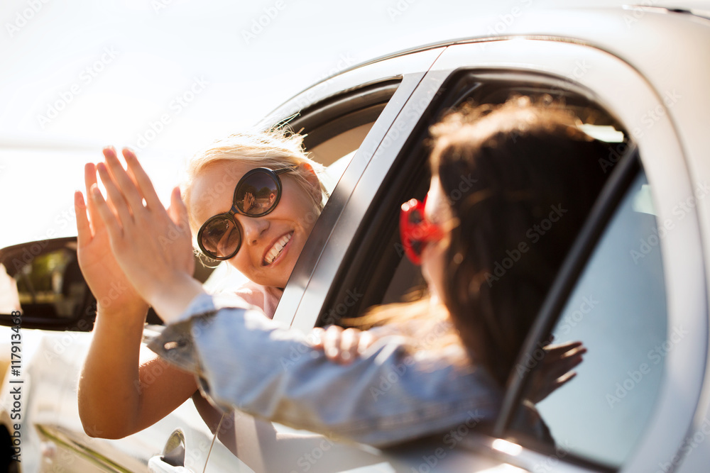 Naklejka premium happy teenage girls or women in car at seaside