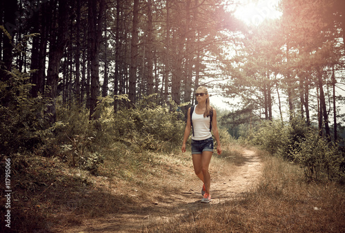 Young sporty female backpacking in the park in the morning. Concept of leisure activity and lifestyle. 