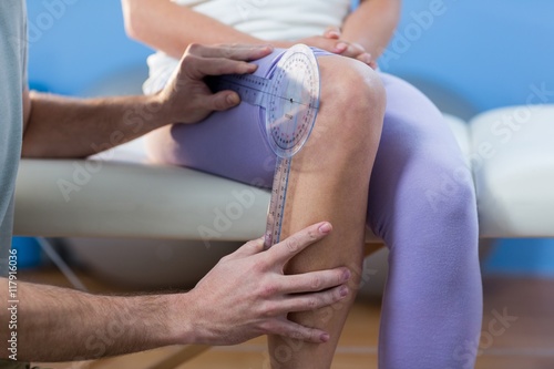 Quadro su tela Physiotherapist examining female patients knee with goniometer