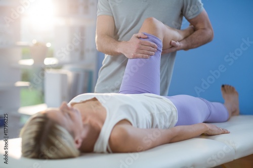 Male physiotherapist giving knee massage to female patient photo