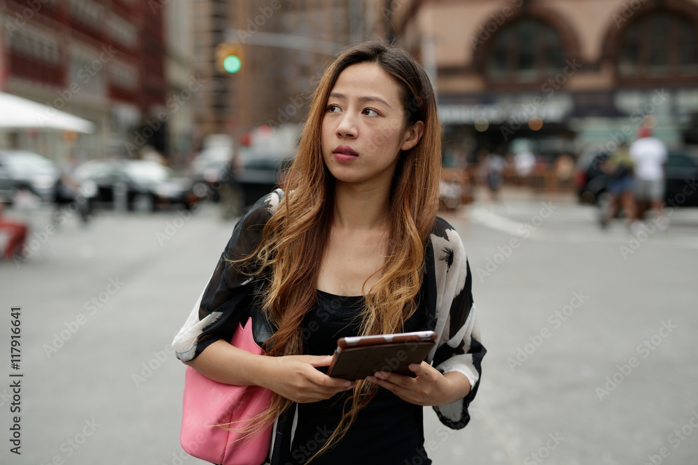 Fototapeta premium Young Asian woman in city using tablet computer 
