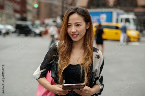 Young Asian woman in city using tablet computer 