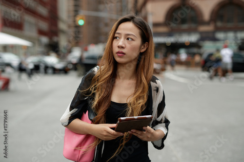 Young Asian woman in city using tablet computer 