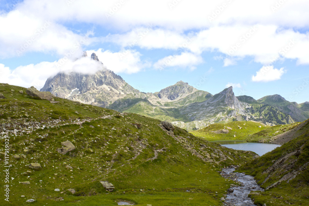 Midi d'Ossau peak behind another mountain and a lake in Ayous Lakes, France Midi d'Ossau peak behind another mountain and a lake in Ayous Lakes, France