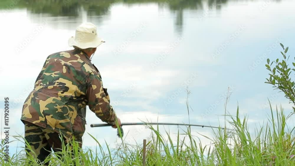 Fisher man with fishing rod catching fish on lake Fisher man with fishing rod catching fish on lake