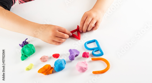 Child hands with colorful clay. Mold letters