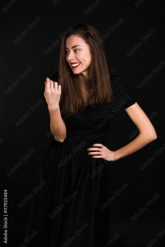 Girl standing in a black dress is laughing and looking away Girl standing in a black dress is laughing and looking away