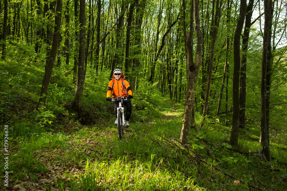 Fototapeta premium Biker in orange jersey on the forest road