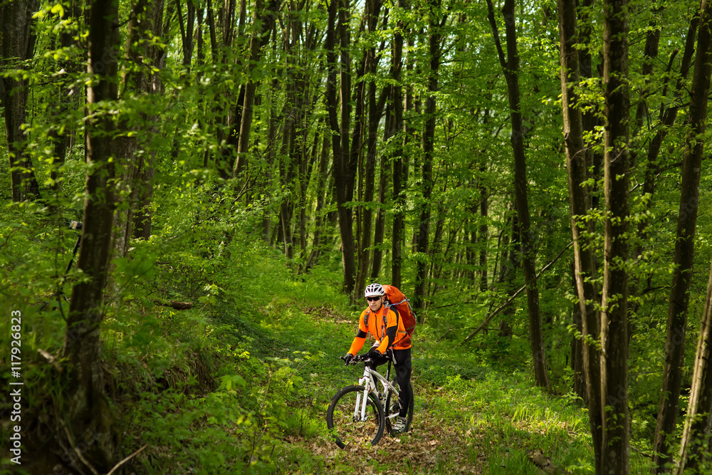 Naklejka premium Biker in orange jersey on the forest road