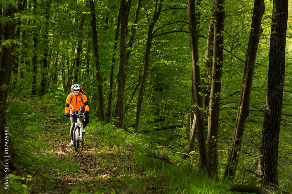Fototapeta premium Biker in orange jersey on the forest road