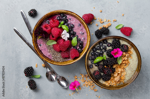 Breakfast berry smoothie bowl topped with blueberries, raspberry, blackberry, chia seeds, oat flakes and muesli for healthy breakfast, selective focus