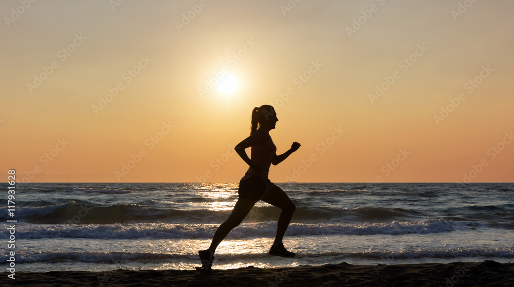 Silhouette einer laufenden Frau am Strand bei Sonnenuntergang