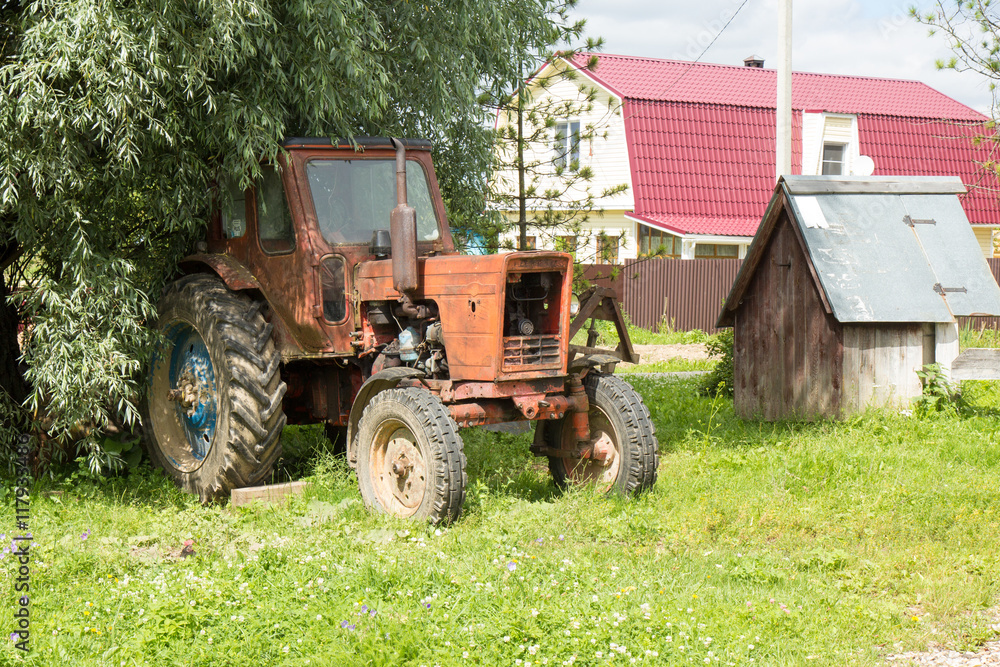 Old red rusty tractor on countryside