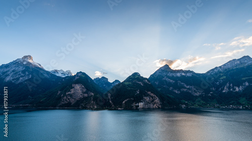 Evening in the Alps. Rays of of the setting sun over the mountain peaks. Lake Uri. Mountainous landscape, wide lens.