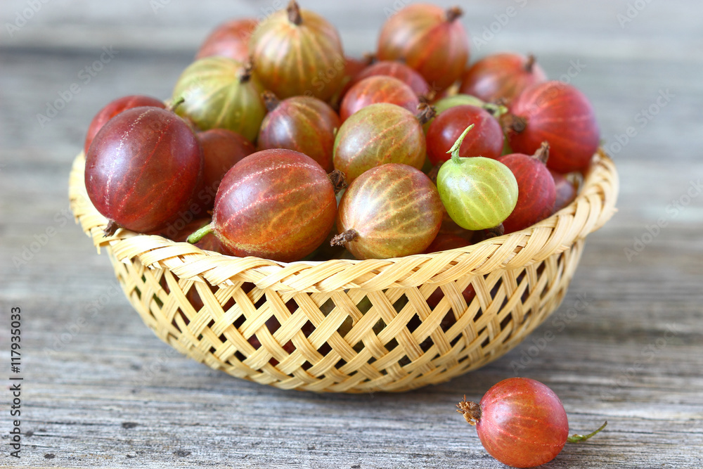 Obraz premium Fresh gooseberries in a basket on a wooden table.