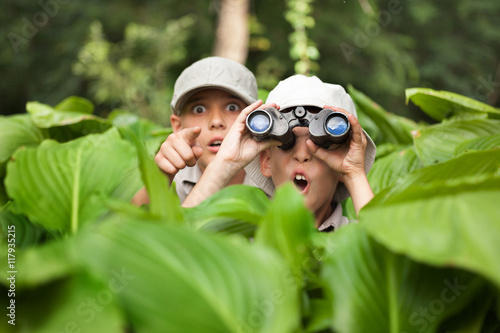excited young campers hiding in grass looking through binoculars photo