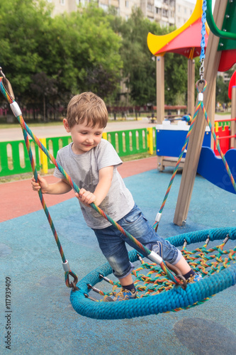 four-year child riding standing on round swing photo