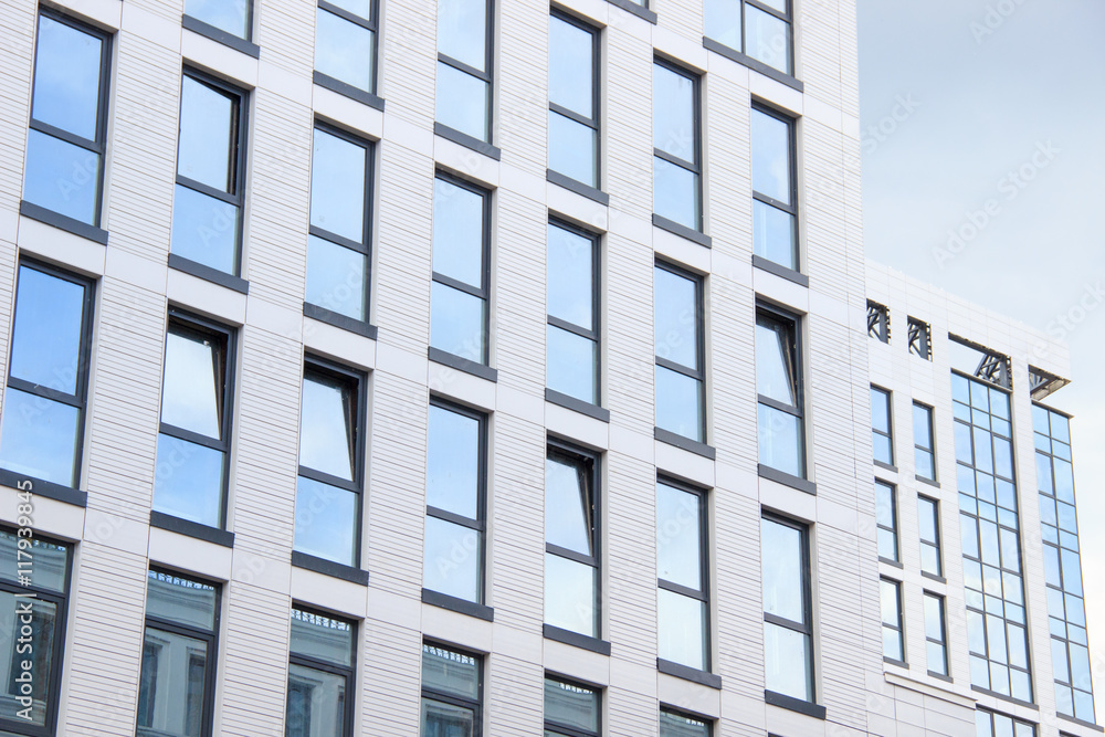A high-rise office building. Some windows opened. Blue sky reflection A high-rise office building. Some windows opened. Blue sky reflection