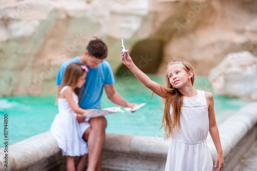 Family with touristic map near Fontana di Trevi, Rome, Italy. Little girl with toy airplane background of Trevi Fountain. Happy father and kids enjoy italian vacation holiday in Europe. © travnikovstudio
