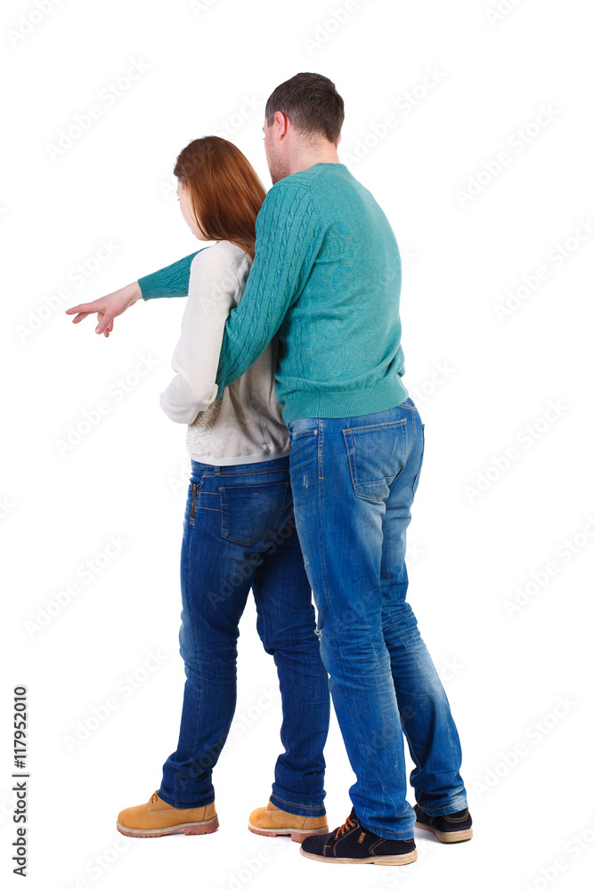 young couple pointing at wal Back view (woman and man). Rear view people collection. backside view of person. Isolated over white background. A man in a green jacket hugged from behind the woman young couple pointing at wal Back view (woman and man). Rear view people collection. backside view of person. Isolated over white background. A man in a green jacket hugged from behind the woman