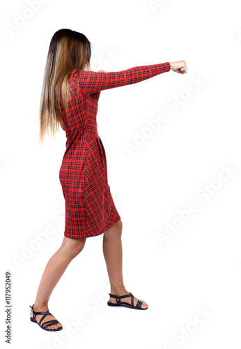 skinny woman funny fights waving his arms and legs. Isolated over white background. The girl in red plaid dress stands sideways and punches.